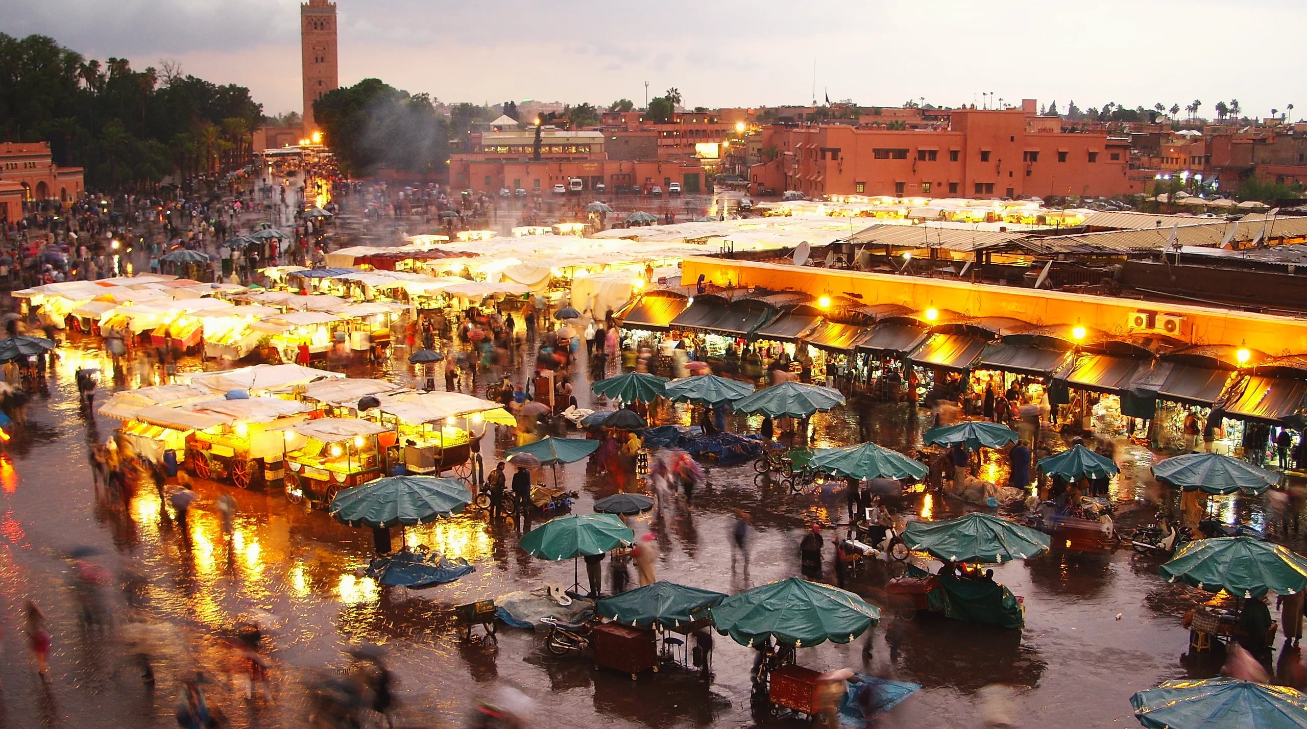 Jemaa el-Fnaa square in Marrakech under a heavy sky, with the Koutoubia minaret behind